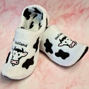 Cow-patterned slippers with Holland text on them.