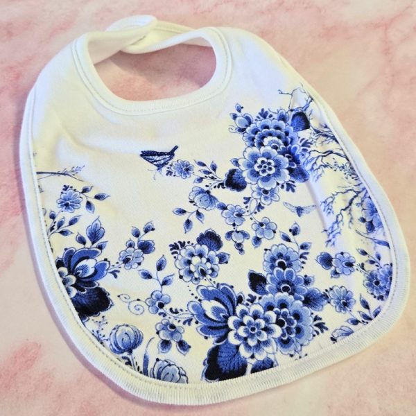 Floral patterned baby bib on pink background.