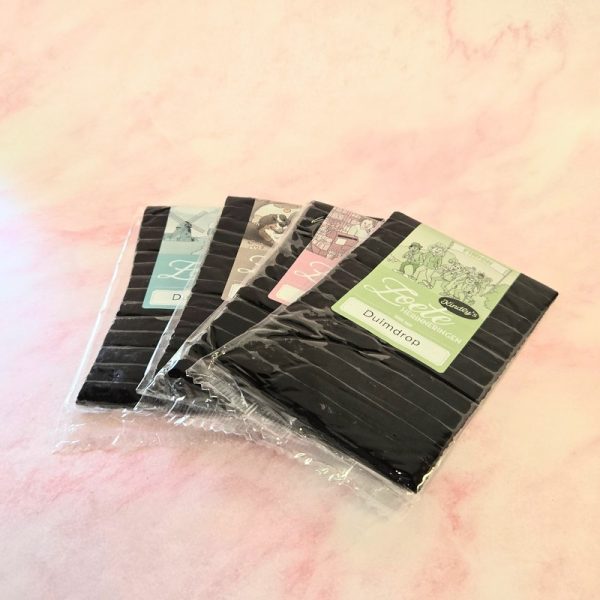 Assorted packs of liquorice candy on pink background.