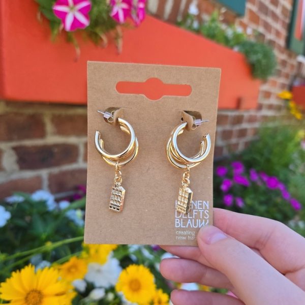 Gold earrings with charm against colourful flowers.